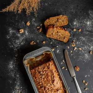 Homemade banana bread in a gray baking pan with sliced pieces.