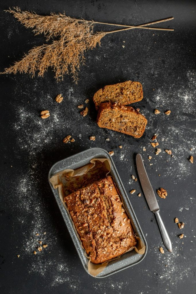 Homemade banana bread in a gray baking pan with sliced pieces.