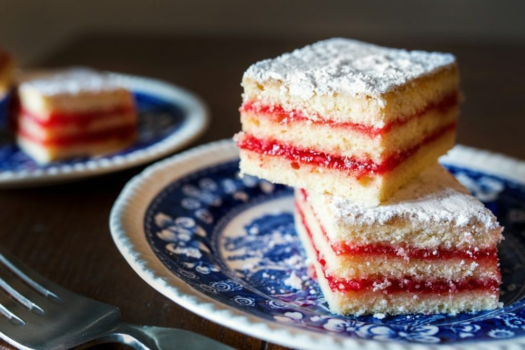 Two square slices of layered cake stacked on a patterned plate.